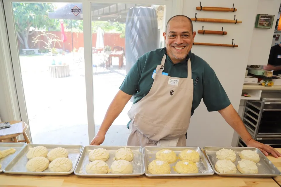 Nacho Varela sonriendo detrás de charolas de conchas en una cocina de pruebas