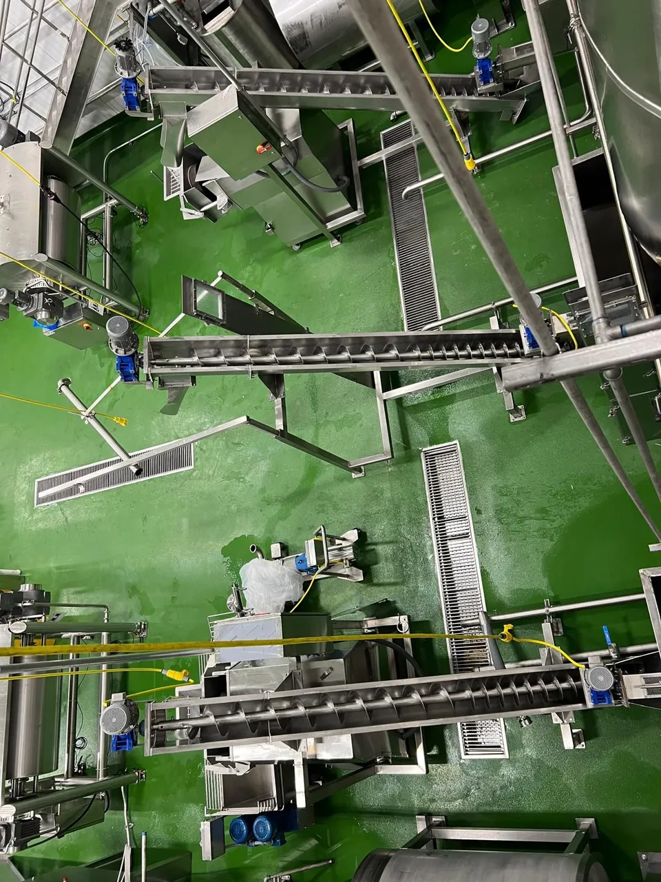 Vista desde arriba de la distribución de una línea en planta: gusanos, coladeras y equipo de acero inoxidable