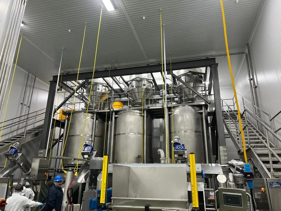 Tanques y tolvas de acero inoxidable sobre un mezzanine en una planta de alimentos